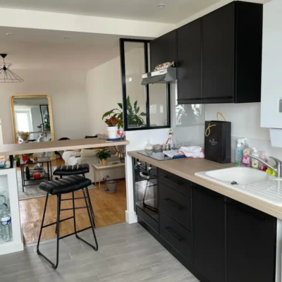 Cuisine moderne noire ouverte sur salon lumineux