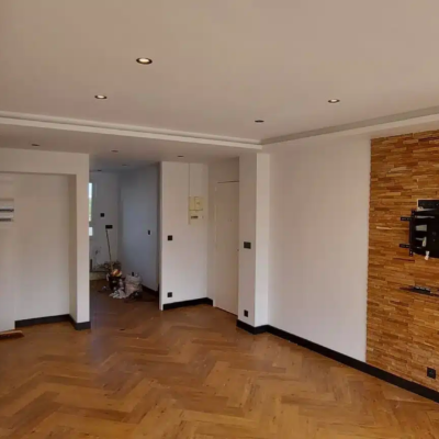 Salon rénové avec parquet chevrons et mur bois